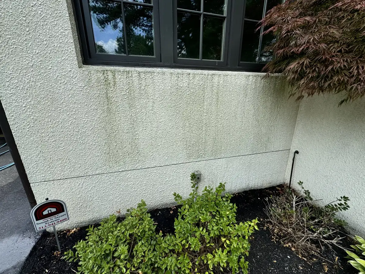 Stucco home exterior with algae and dirt streaks before soft washing by Skyline